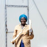 Medium Shot An Entreprenuer Holding Peeled Cassava Tubers Outside A Solar Drier